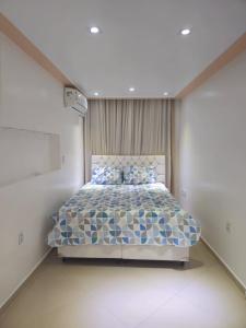 a bedroom with a bed with a blue and white bedspread at Apartamento aconchegante para temporada in Salvador +29 photos