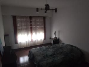 a bedroom with a bed and a window with curtains at Casa chalet neco in Necochea +1 photo