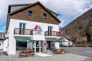 un edificio con due tavoli da picnic di fronte di Apart Hôtel des Cols a Bordères-Louron