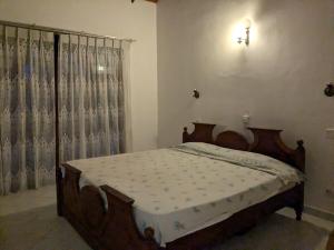 1 dormitorio con cama de madera frente a una ventana en Tranquil Apt with Scenic Balcony, en Bopitiya