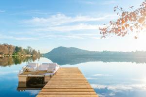 a dock with two white chairs on a lake at Villa Evelina in Travedona