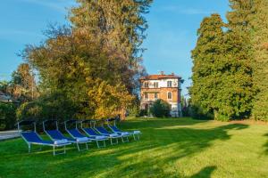 a group of blue chairs sitting in the grass in front of a house at Villa Evelina in Travedona +21 photos
