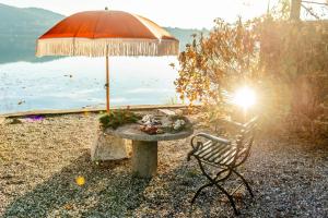 a table with an umbrella next to a lake at Villa Evelina in Travedona