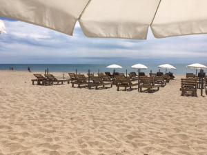 a beach with tables and chairs and umbrellas at Spacieux et lumineux duplex arty au centre de Sète in Sète