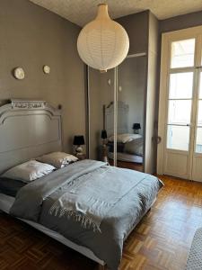 a bedroom with a large bed and a chandelier at Spacieux et lumineux duplex arty au centre de Sète in Sète