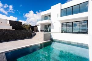 una casa blanca con una piscina delante de ella en Exclusive 6 bedrooms Villa in Lanzarote - Ocean & Volcano Views, Private Pool, Jacuzzi & Gym, en Mácher