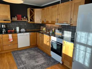 a kitchen with wooden cabinets and white appliances at Spacious 3BR Apartment - Fast Wi-Fi - Free Parking - Near Oslo Airport & City - Les Homes in Gjerdrum