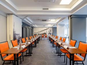 a row of tables in a room with orange chairs at Mercure Czestochowa Centrum in Częstochowa