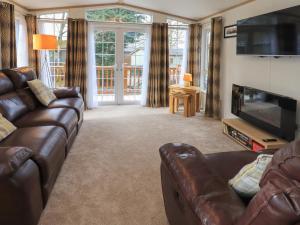 a living room with a leather couch and a television at Squirrels Snug in Windermere