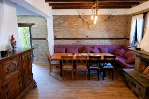 a dining room with a table and a purple couch at Трите къщи in Leshten