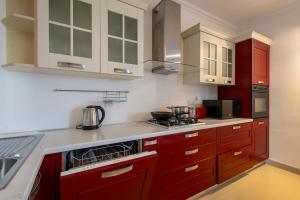 a kitchen with red cabinets and a stove top oven at Penthouse Near Paceville with Private Terrace by QuickTrips in Is-Swieqi