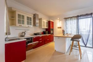 a kitchen with red and white cabinets and a counter at Penthouse Near Paceville with Private Terrace by QuickTrips in Is-Swieqi