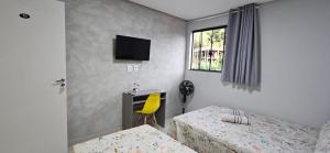 a bedroom with two beds and a desk and a television at Hotel Real in Ouro Preto