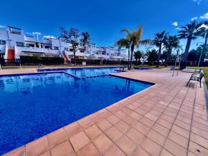 a swimming pool with palm trees and a building at Condado De Alhama, Jardin 10 SV54 in Alhama de Murcia