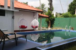 a pool with two chairs next to a house at Blue water Villa in Weligama