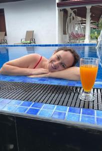 a woman laying on a table in a swimming pool with a drink at Blue water Villa in Weligama