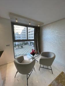 a living room with two chairs and a table and a window at Appartement al aamira in Tangier