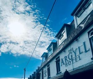 Un edificio in una strada con il sole nel cielo di Argyll Hotel a Ullapool