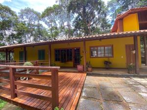 a yellow house with a wooden deck at Yellow House Santa Clara in Bocaina de Minas