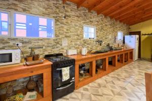 a kitchen with a stove and a stone wall at Hostel Familia de Campo in El Chalten
