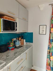 a kitchen with white cabinets and a microwave at Penthouse in Luxor House in London