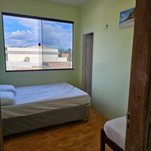 een slaapkamer met twee bedden en een groot raam bij Casa Mandacaru in Ubajara