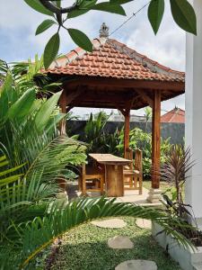 a wooden gazebo with a table and a bench at Kampana Homestay in Uluwatu