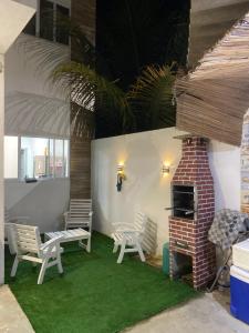 a living room with chairs and a brick fireplace at Casa paraíso dos milagres in São Miguel dos Milagres