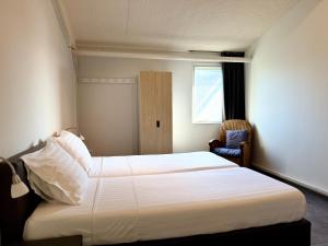 a bedroom with a large white bed and a chair at Appartementen Casa del Lago in Lisse +73 photos