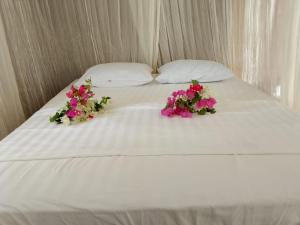 białe łóżko z dwoma kwiatami na górze w obiekcie Black Coral Raja Ampat Homestay w mieście Poelau Mansoear