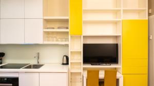 a kitchen with yellow and white cabinets and a tv at Luxury Flat - WiFi, AC, Walk to Brera & Duomo in Milan +13 photos