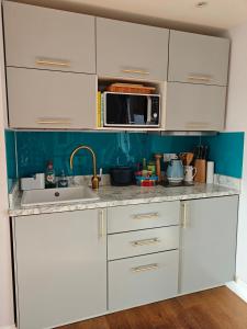 a kitchen with white cabinets and a microwave at Penthouse in Luxor House in London +7 photos