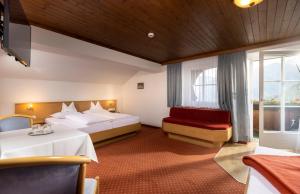 a hotel room with two beds and a chair at Der Oswalderhof in Obertilliach