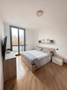 a white bedroom with a bed and a large window at Bed & Bergamo Casa Vacanze in Bergamo
