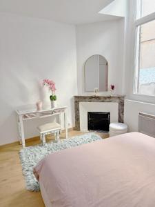 a white bedroom with a bed and a fireplace at Art&Heart - Centre historique in Béziers