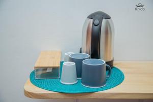 Eine Kaffeemaschine und vier Tassen auf einem Tisch in der Unterkunft Il Nido Cotonou in Cotonou