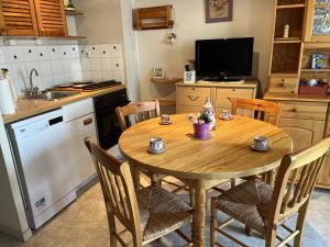 a kitchen with a wooden table with chairs and a television at Les Fermettes in Saint-Jean-de-Monts +7 photos