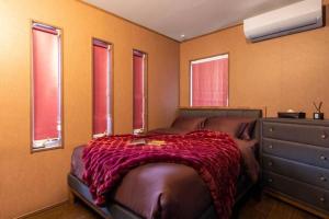 sypialnia z łóżkiem przykrytym czerwonym kocem w obiekcie Vacation Rental Motobu Grande BBQ機材完備 w mieście Motobu +30 zdjęć