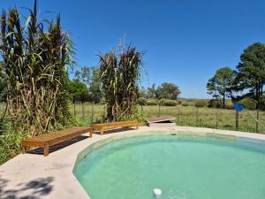 a swimming pool with two benches and a bench at Chacra mita í in La Cruz