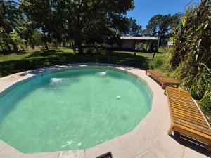 a swimming pool with two benches and a pool at Chacra mita í in La Cruz