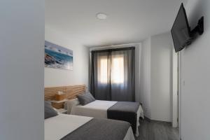 a small room with two beds and a television at MM-Rooms in San Javier