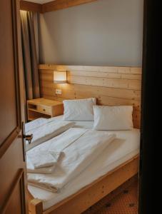 een slaapkamer met een groot bed met witte lakens en kussens bij Appartement Conrad in Saalbach Hinterglemm