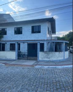 a white house with a gate in front of a street at Hostel Dunas & Mar - Hostel e Suítes - Cabo Frio in Cabo Frio
