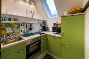 una cocina verde con armarios verdes y fregadero en FeWo Schöna45, en Schöna