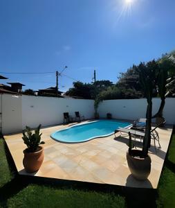 a swimming pool in a yard with two potted plants at Linda casa com estilo buziana in Búzios