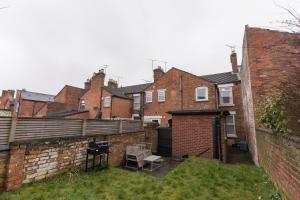 un patio trasero con una pared de ladrillo y algunos edificios en Entire home in Staffordshire, en Stafford