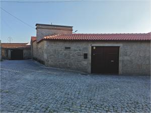 un edificio in pietra con garage e vialetto di mattoni di Casa do Muro Alto a Alvelos