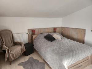 a bedroom with a large bed and a chair at La maisonnette du marais in Amuré
