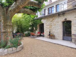 a stone house with a patio and a tree at Mas Tareau Chambres d Hotes in Beaucaire