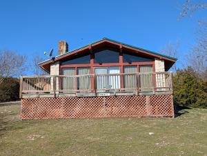 a house with a large deck on top of a yard at Cedarvale Cabins Turner Falls in Davis
